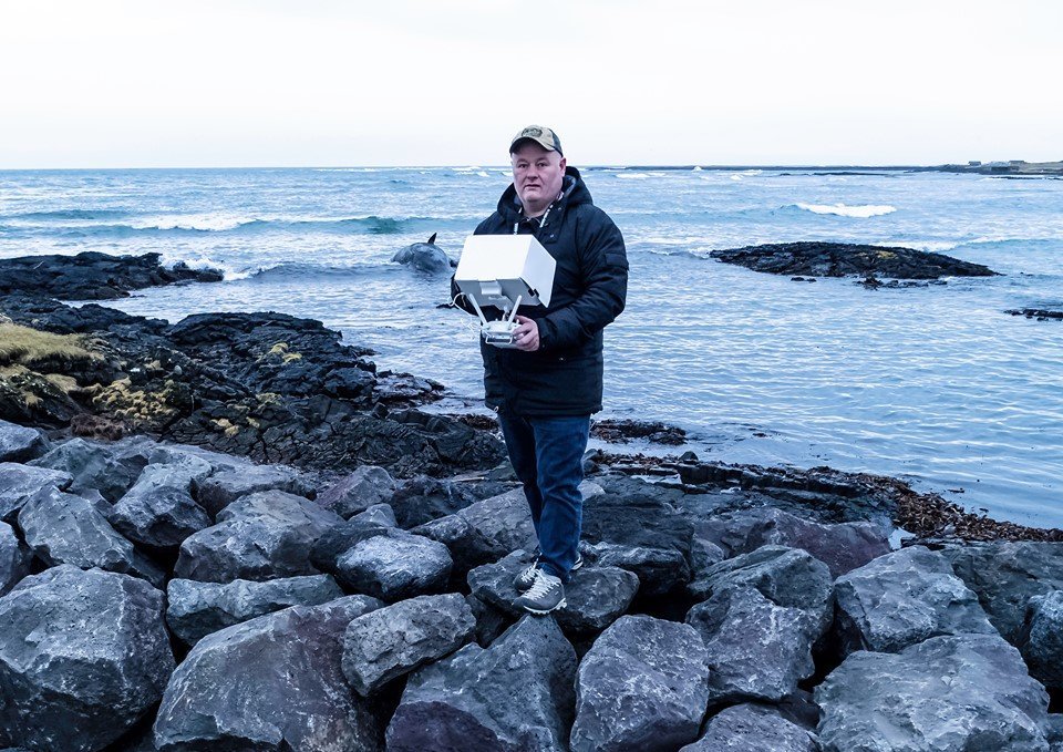 Jón Steinar að störfum. Með drónafjarstýringuna og búrhvalinn sem strandaði við Grindavík í baksýn.